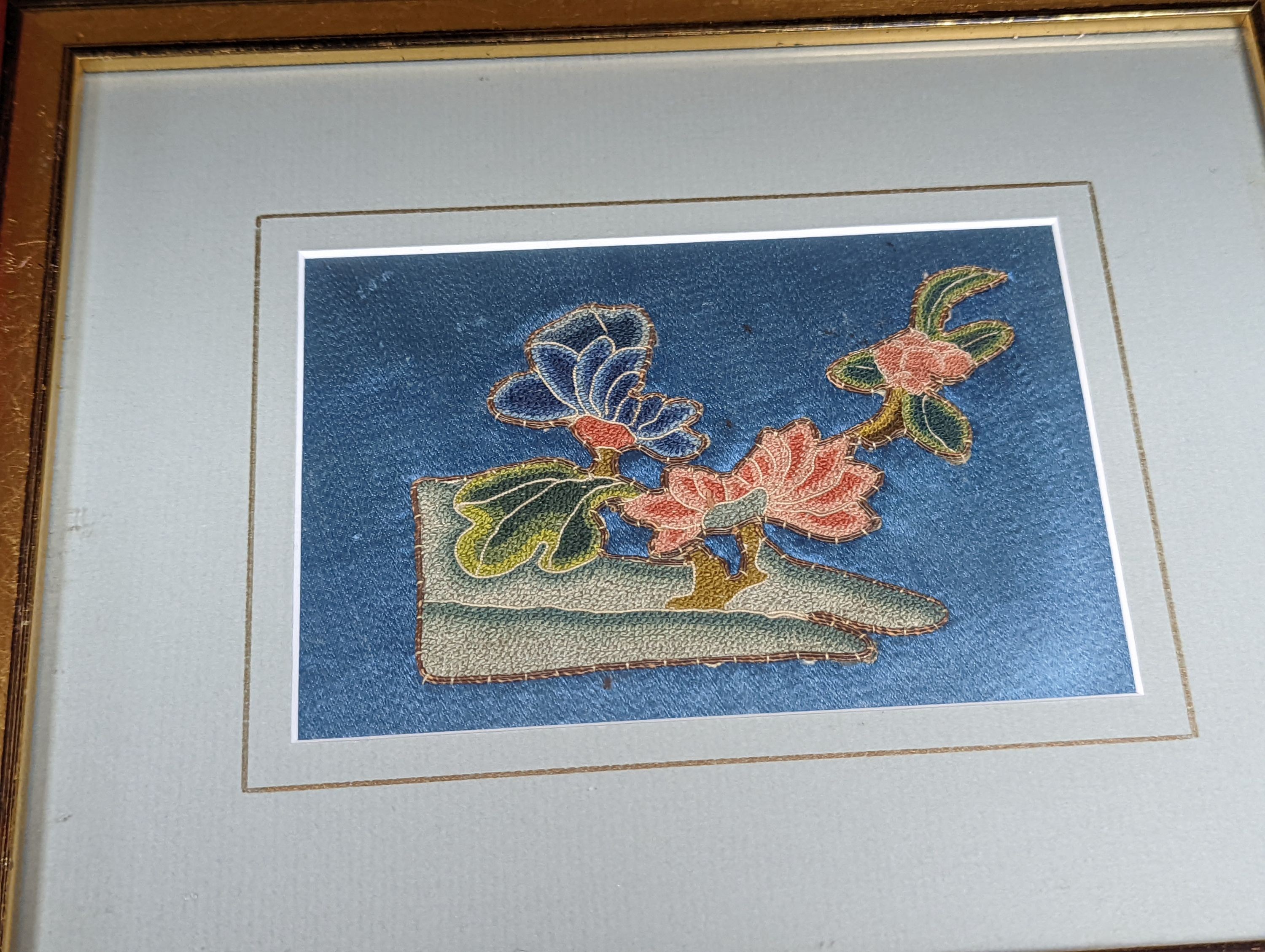 A set of four Chinese silk embroidered motifs, a pair of floral silk motifs and a later pair f sleeve bands, all framed